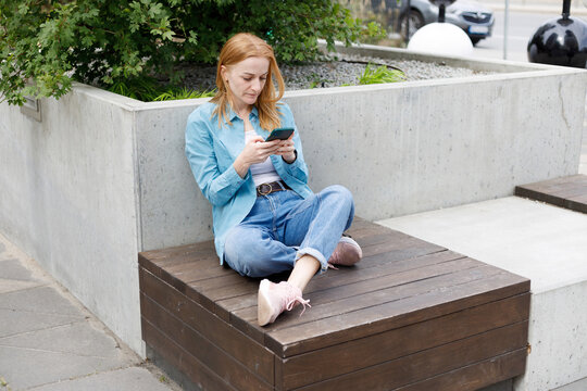Woman Using Smartphone Outdoors in Warsaw Urban Park