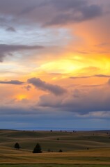Obraz premium Vibrant sunset over rolling hills and plains.