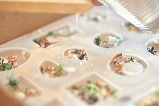 Handcrafted epoxy resin jewelry mold with shells and flowers in artistic process.