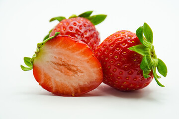 Three strawberries with strawberry leaf on white background.