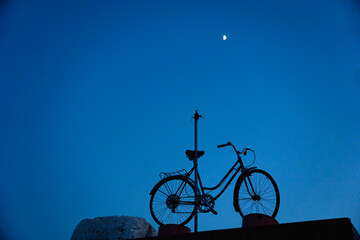 Bike on a background of blue sky and bright moon at dusk - night cycling