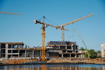 cranes at the construction site , construction of a large building on the city embankment , urbanization