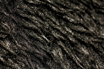 Smooth soft dirty black color furry, fluffy and hairy artificial sheep skin plush fur wool rug texture cloth knitted coarse background surface pattern for beauty and fashion concepts. Close up view.