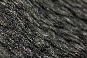 Smooth soft dirty black color furry, fluffy and hairy artificial sheep skin plush fur wool rug texture cloth knitted coarse background surface pattern for beauty and fashion concepts. Close up view.