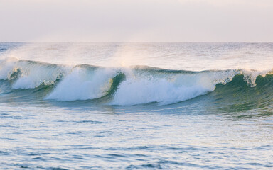 Wave breaking with water spray behind it.