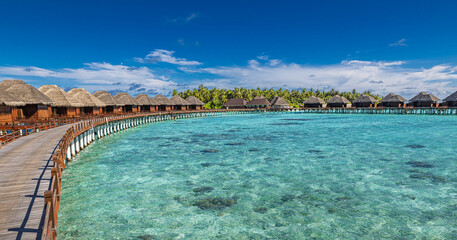 Beautiful sunny tourism destination tropical beach, Maldives. Jetty pathway into tranquil paradise island. Luxury water villas blue sea, perfect summer vacation landscape or holiday beachfront coast