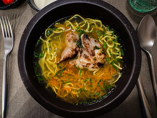 Quail Noodle Soup in stylish black bowl restaurant , Broth with Noodles and Vegetables, Comfort Food, Zeama, Traditional Moldavian and Romanian Soup.