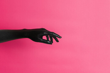 Black painted elegant woman's hand on her skin gesticulates on pink background. High Fashion art...