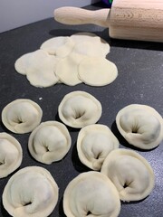 Freshly made pelmeni with a rolling pin on a kitchen table