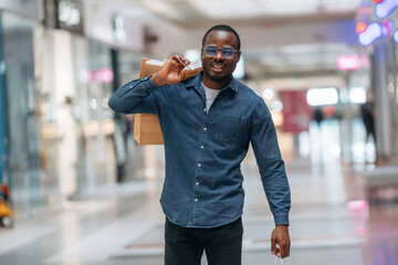 Walking and holding shopping bags. Black man is in the hall of the supermarket