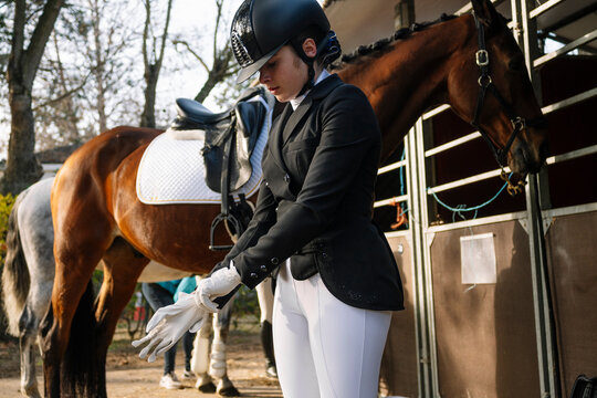 Teenager in classical dressage attire preps by the horse