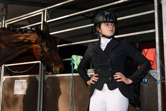 Teenager in classical dressage attire standing beside a horse