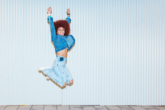 Joyful African descent woman jumping against white background