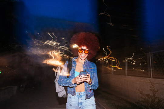 African descendent woman using smartphone at night