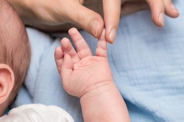 mother holding baby by finger on hand close-up