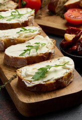 Cream cheese spread on ciabatta pieces and decorated with arugula leaves, appetizer