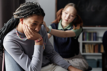 Candid portrait of Black teenage girl crying during support group session with caring friend...