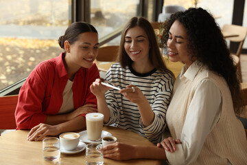 Woman taking picture of coffee drinks during meeting with her friends in cafe