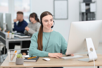 Saleswoman talking to client via headset at desk in office
