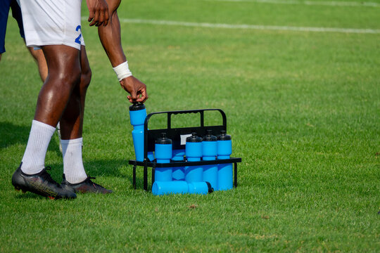 Soccer player refreshing with bottle of fresh water or energy drink on football field