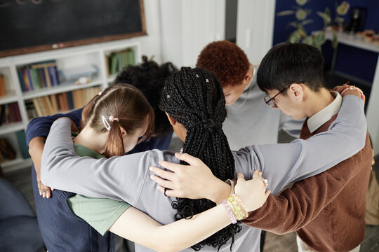 High angle view at multiethnic group of teenagers huddling in circle during motivational group exercise in school - Powered by Adobe