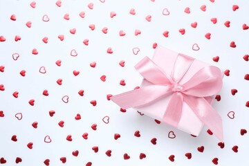 Beautiful gift box with red hearts on color background