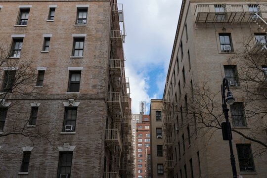 Urban alley with brick buildings and fire escapes.