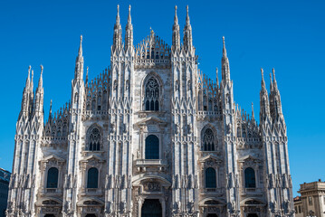 Fototapeta premium View of the Milan Cathedral. Duomo di Milano. Overview of the facade of the cathedral in white marble. Buttresses, pinnacles and spiers. Statue of the Madonnina. Lombardia