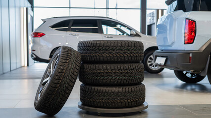 New wheels with studded tires against the background of new cars. 