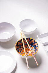 patterned bowl with chopsticks and white background
