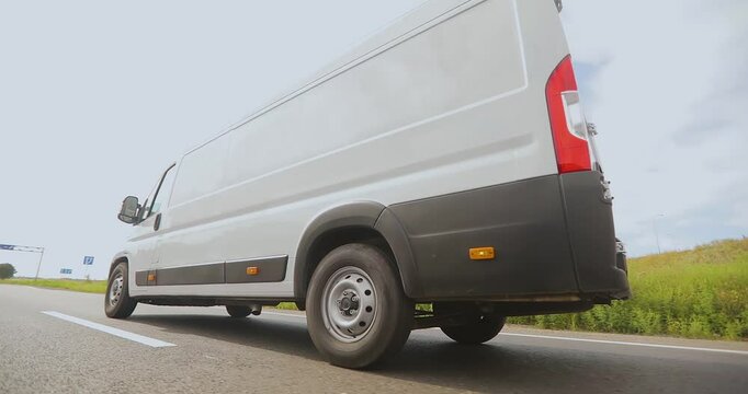 A white delivery or service van is driving down the road. White Cargo minibus driving along the highway. - Powered by Adobe