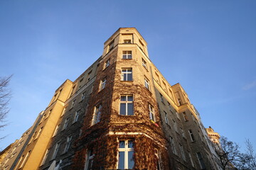 Sch&ouml;ner Altbau als Eckhaus in Beige und Naturfarben mit begr&uuml;nter Fassade im Winter vor blauem Himmel im Sonnenschein an der Sch&ouml;nhauser Allee in Berlin-Mitte in der Hauptstadt Berlin