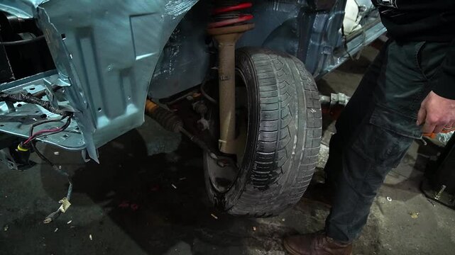 young mechanic repairs and installs an old gray car after a road accident (157)