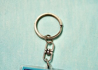 Key chain round silver metal ring hook clip isolated on horizontal light blue background.