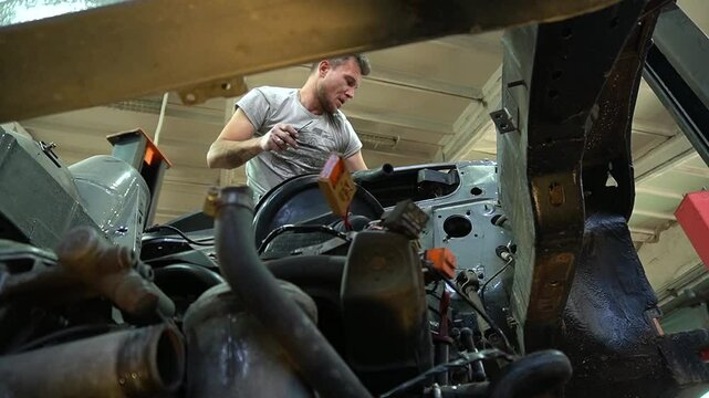 young mechanic repairs and installs an old gray car after a road accident (157)