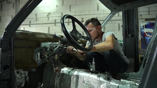 young mechanic repairs and installs an old gray car after a road accident (157)
