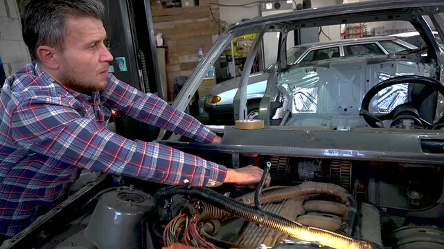 young mechanic repairs and installs an old gray car after a road accident (157)