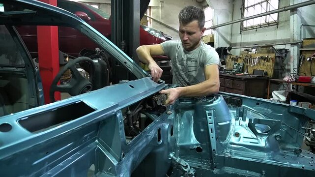 young mechanic repairs and installs an old gray car after a road accident (157)