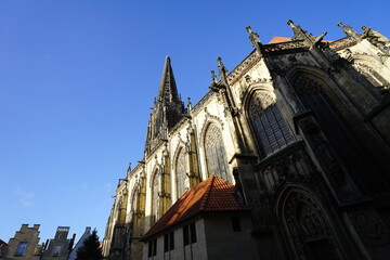 Seitenansicht der r&ouml;misch-katholischen Kirche Sankt Lamberti mit Kirchturm vor blauem Himmel im Sonnenschein am Prinzipalmarkt in der City und Altstadt von M&uuml;nster in Westfalen im M&uuml;nsterland