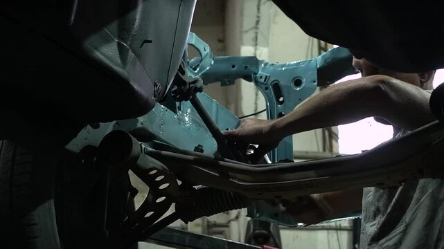 young mechanic repairs and installs an old gray car after a road accident (157)
