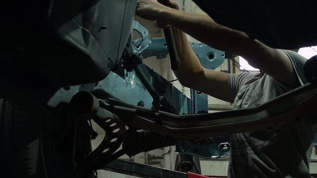 young mechanic repairs and installs an old gray car after a road accident (157)