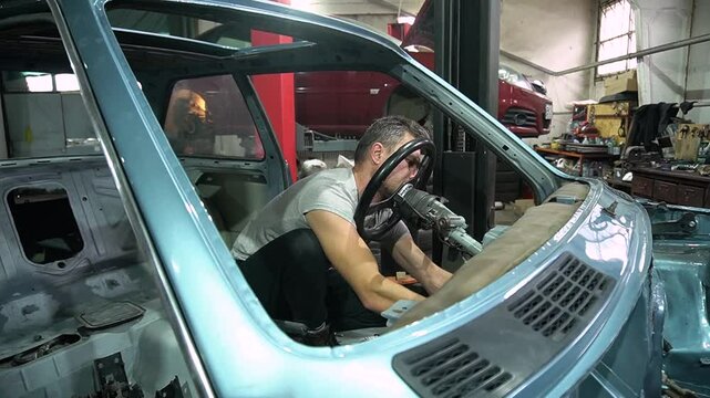 young mechanic repairs and installs an old gray car after a road accident (157)