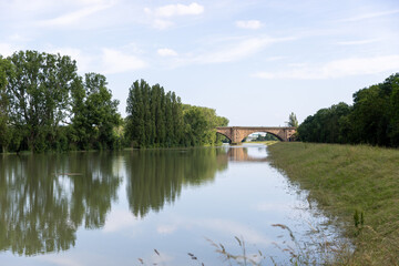 Obraz premium a stone bridge with two arches spanning over a calm river or canal.