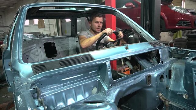 young mechanic repairs and installs an old gray car after a road accident (157)
