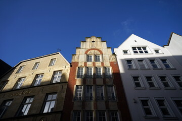 Fototapeta premium Schöne restaurierte Giebelhäuser mit Spitzgiebel und Treppengiebel vor blauem Himmel im Sonnenschein in der City und Altstadt von Münster in Westfalen im Münsterland