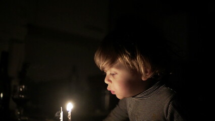 Cute child blowing birthday candles. Toddler boy celebrates anniversary, relighting magic candle