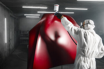Car paint job by professional worker, car painting procedure in car service, body paint garage. 