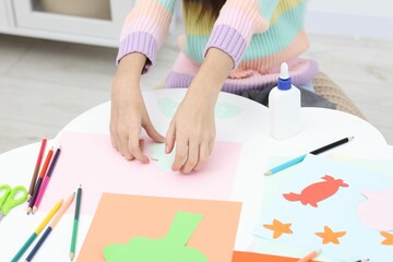Girl making art project at table indoors, closeup
