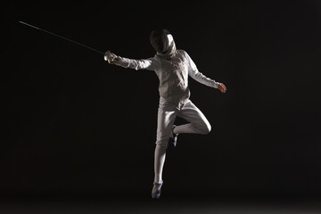 Fencer with epee practicing on black background