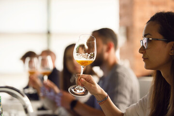 Woman Looking and Analyzing Color of Beer. Group of Participants Tasting Beer on Beer Craft...